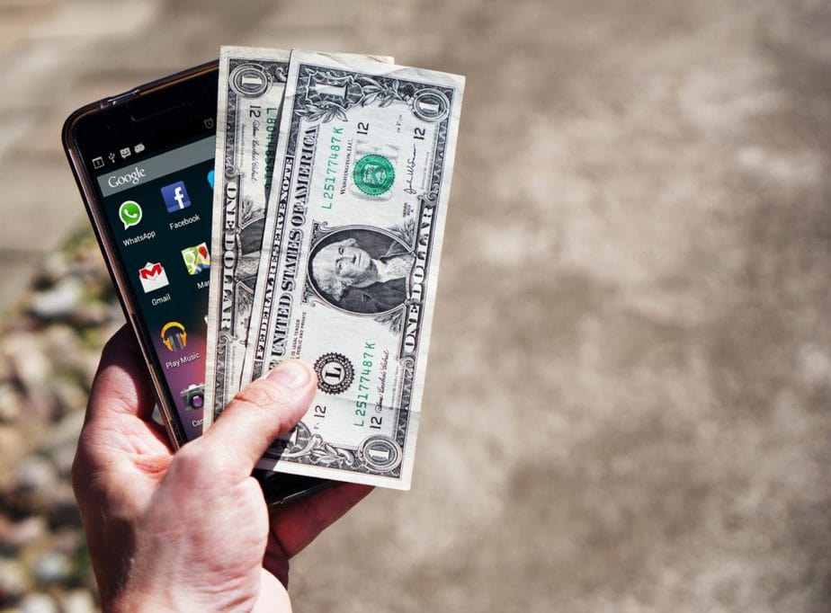 Person holding smartphone and dollar bills