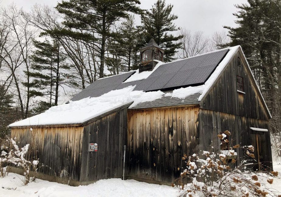 Snow on barn roof with solar panels in new england